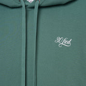 Sweatshirt unissexo com capuz da marca 30Fied, em tom verde. Modelo oversized de manga comprida, com capuz e cordões ajustáveis. Apresenta bordados e estampados diferenciadores que destacam o design.