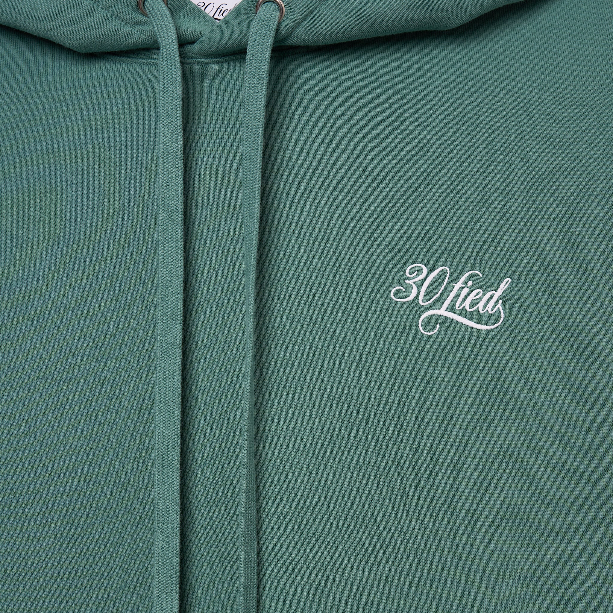 Sweatshirt unissexo com capuz da marca 30Fied, em tom verde. Modelo oversized de manga comprida, com capuz e cordões ajustáveis. Apresenta bordados e estampados diferenciadores que destacam o design.